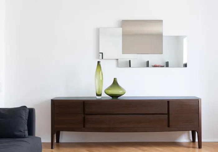 Sideboard aus dunklem Massivholz vor einer hellen Wand