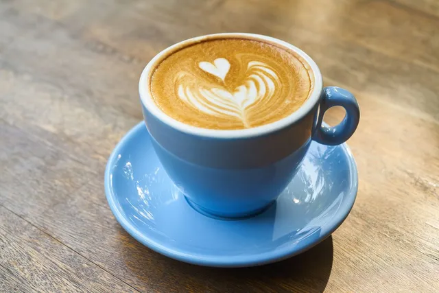 Cappuccino mit einem Herz aus Milchschaum in einer hellblauen Tasse