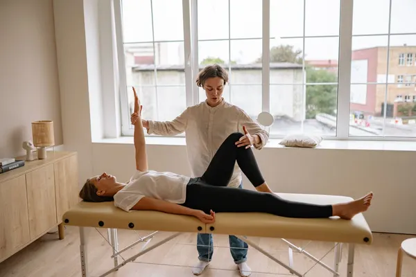Heller Behandlungsraum mit Therapieliege und bodentiefen Fenstern