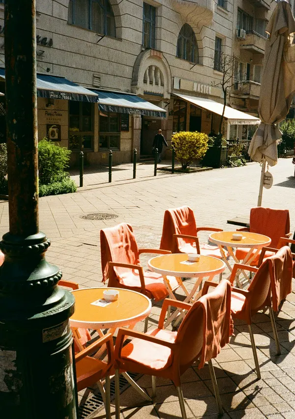 Sonnige Café-Terrasse mit orangefarbenen Stühlen